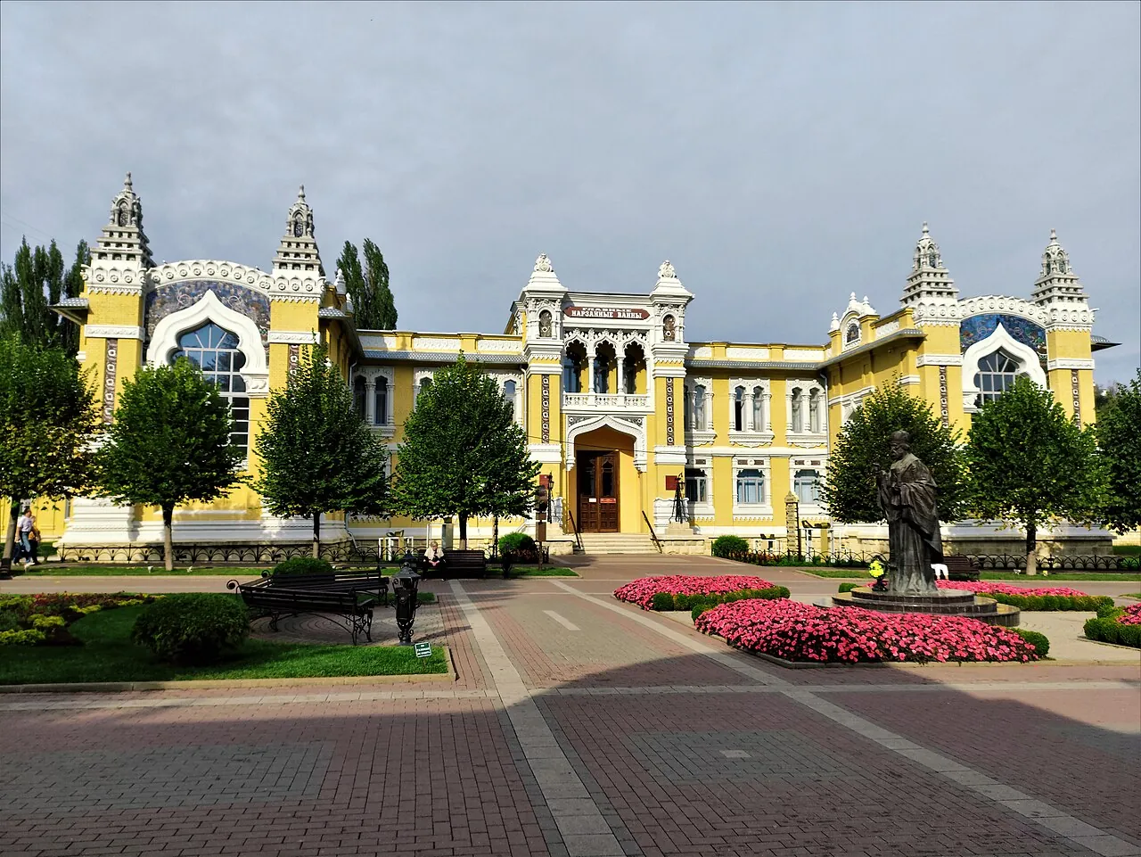 Главные нарзанные ванны: жёлтое здание с башенками, перед ним клумбы и памятник